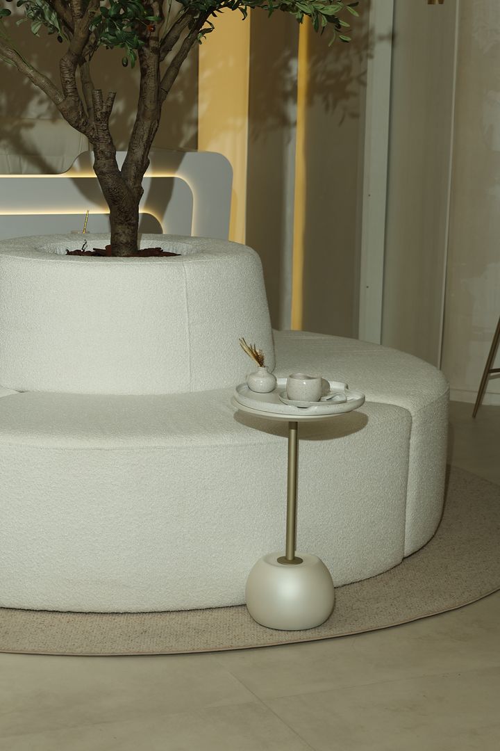 Sofá curvo em volta da oliveira, com uma mesa lateral e café servido